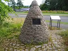 a grassy area with a triangular stone cairn in it