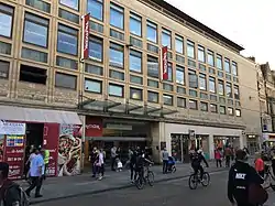 An entrance to a shopping centre on a busy shopping street, with a Gap store and signs for TK Maxx