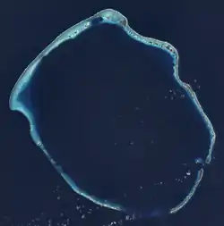 Light blue circle (a reef) with green splotches (islands) is surrounded by deep blue (the ocean) and surrounds deep blue (the lagoon)