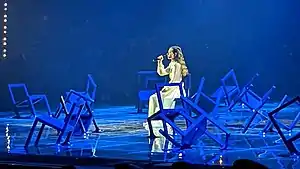 Tenfjord performing seated on the Eurovision stage surrounded by broken chairs
