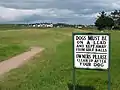 Warning sign with the club house in the distance