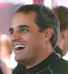 Head portrait of a man in his late thirties. He is facing to the left and smiling.