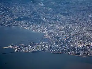 View of coastal city with higher-rise buildings and a port in the foreground and lower-rise buildings further away