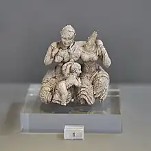 Ivory figurine showing three figures; two seated women and a child between them
