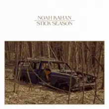 The shell of a car in the middle of barren trees