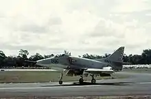 Colour photograph of a white military jet fighter taxiing along a runway