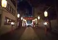 Walking along the lit path of Torii at night at Hanazono Jinja