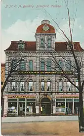 Colour postcard depicting a four-storey building construction in grey granite with a red-coloured roof